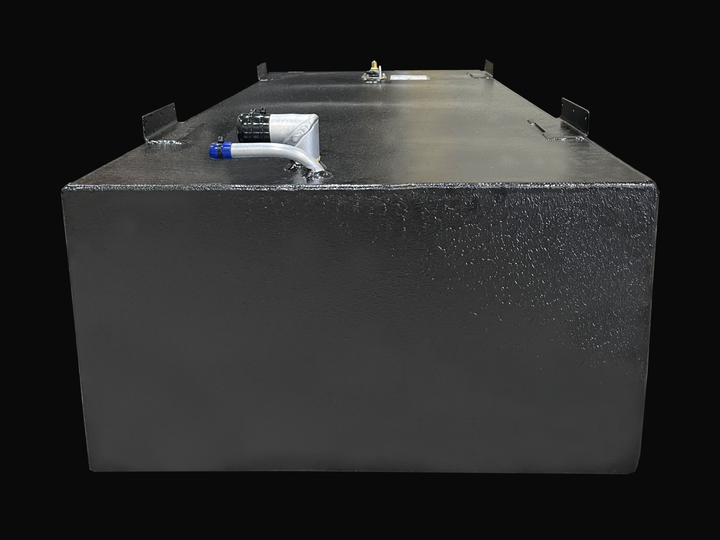 A wide, low-angle photo of a long, rectangular, dark, textured boat fuel tank. The top surface shows various fittings, including a white fitting with a blue hose connector near the front, and black mounting tabs on the corners, against a black background.