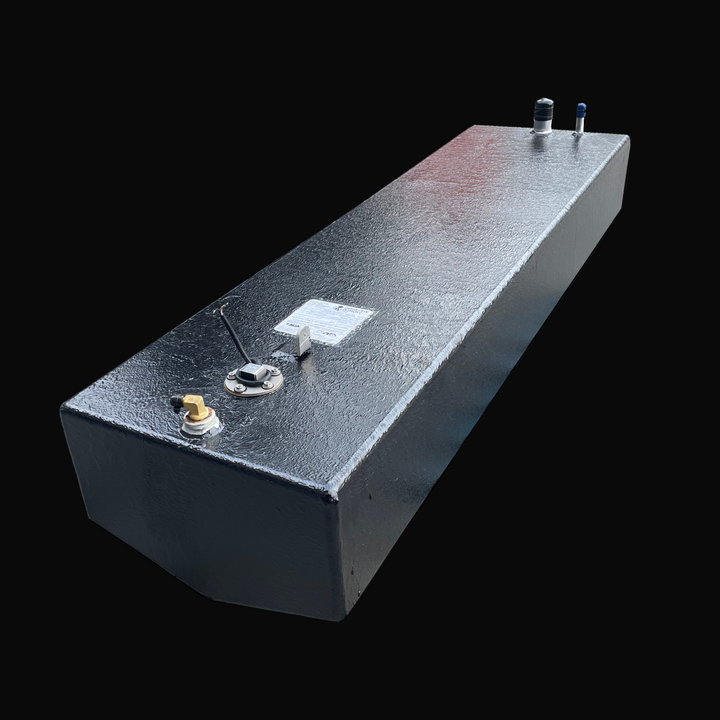 A long, dark-colored, textured boat fuel tank, shown angled from the front. The top surface features a fuel sending unit, a specification plate, and various fittings, against a solid black background.