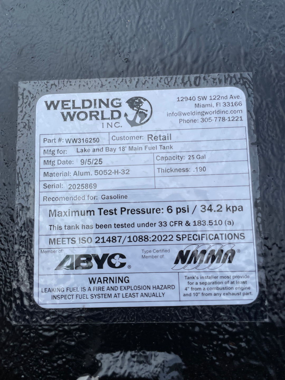 A close-up of a white specification label on a dark textured boat fuel tank. The Welding World Inc. label lists the part as WW316250, manufactured for a "Lake and Bay 18' Main Fuel Tank," with a 25-gallon capacity.