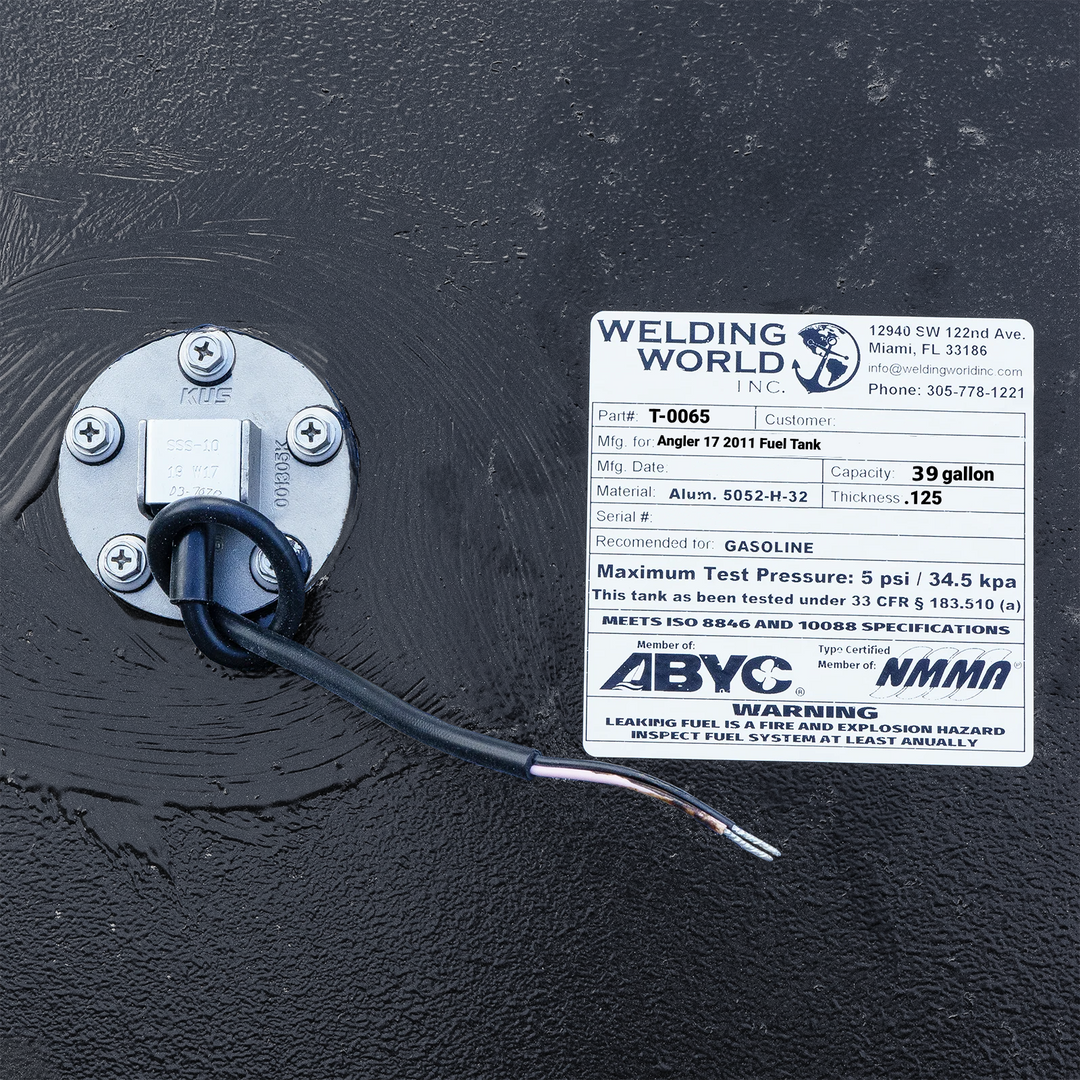 Top-down technical view of an Angler 17 marine fuel tank surface, showcasing the ABYC and NMMA certified data plate and the fuel level sending unit. The image highlights the heavy-duty coal tar epoxy finish and the electrical wiring leads for the sender, confirming the tank meets USCG 33 CFR § 183.510 (a) safety specifications.