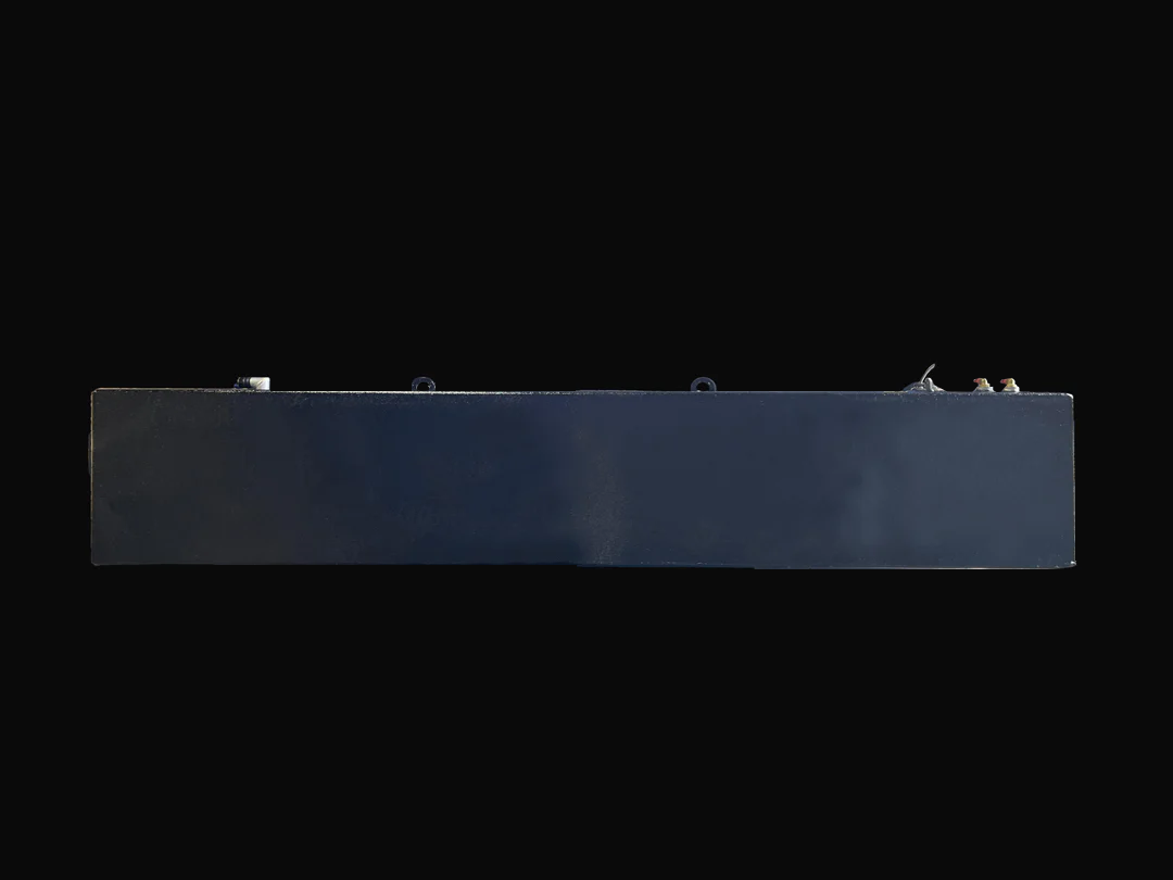 A long side profile photo of a dark, textured boat fuel tank, showing various fittings and D-rings on its top surface, against a black background.