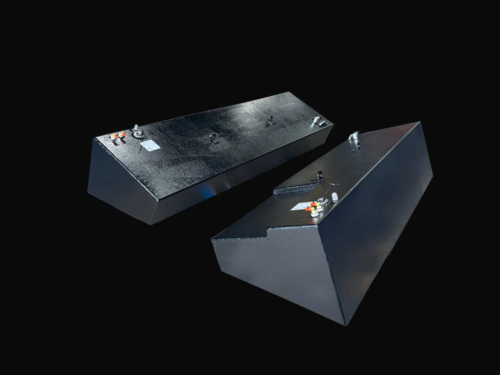 A photo of a pair of dark, textured boat fuel tanks, one long and wedge-shaped and the other with a stepped design, shown angled side-by-side against a black background.