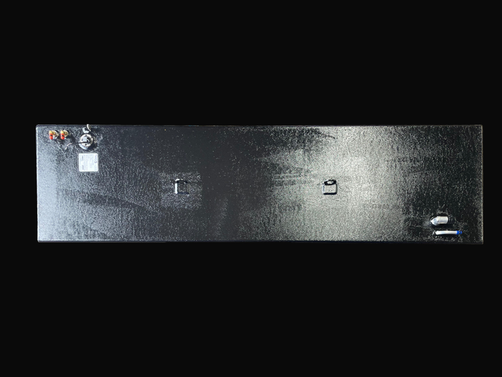 A direct top-down photo of a long, dark, textured boat fuel tank, showing its various top-mounted fittings, D-rings, and specification plate against a black background.