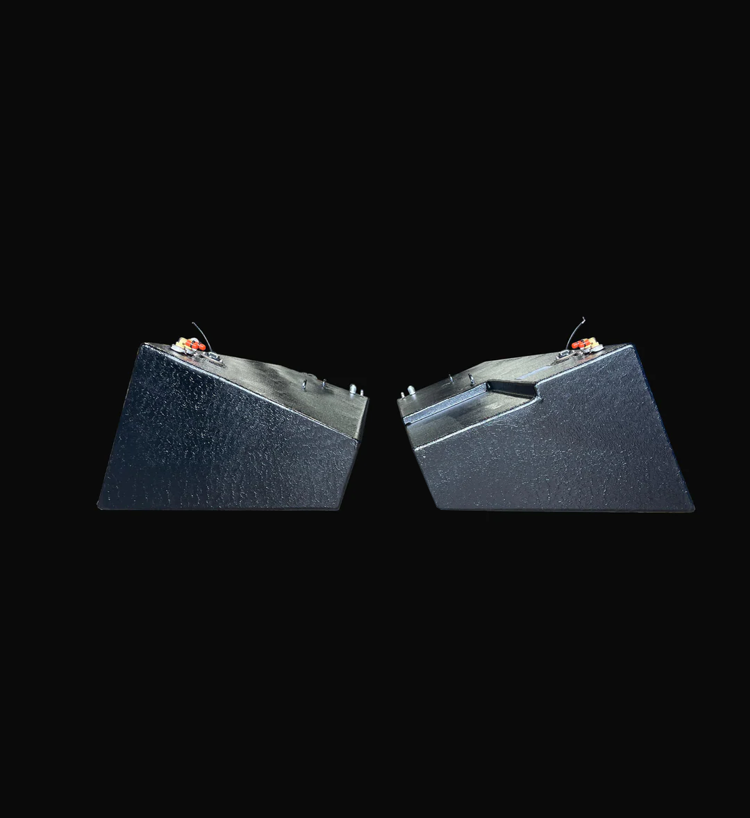 A profile photo showing the ends of a pair of dark, heavily-textured boat fuel tanks side-by-side. The tank on the right features a stepped top surface, while the tank on the left is flat, both isolated against a black background.