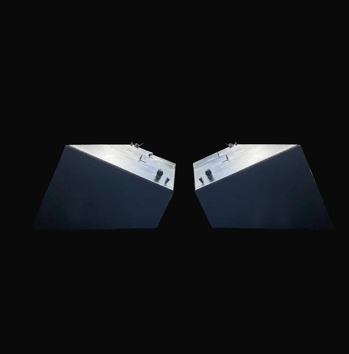A profile photo showing the angled ends of a pair of dark, textured, wedge-shaped boat fuel tanks, shown side-by-side against a black background.