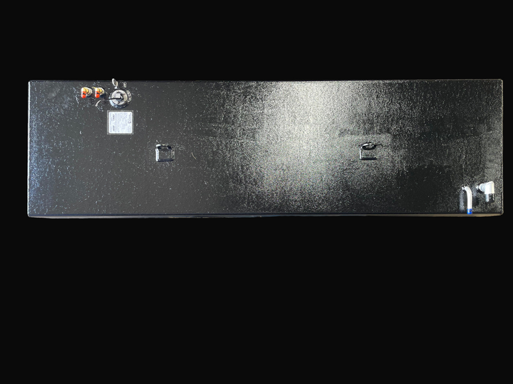 A direct top-down photo of a long, dark, textured boat fuel tank, showing its various top-mounted fittings, D-rings, and specification plate against a black background.