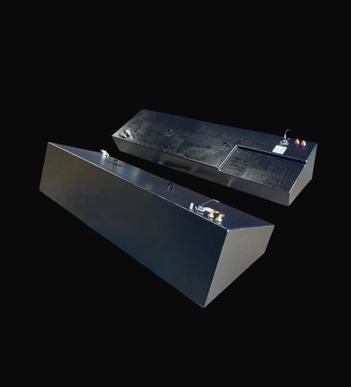 A photo of a pair of dark, textured boat fuel tanks, shown angled and side-by-side from a high-angle perspective. One tank is wedge-shaped, and the other has a stepped design, all against a black background.