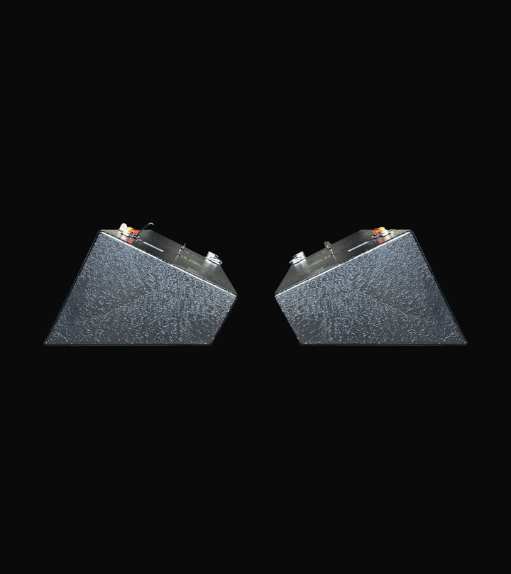 A profile photo showing the ends of a pair of dark, heavily-textured, wedge-shaped boat fuel tanks, isolated against a black background.