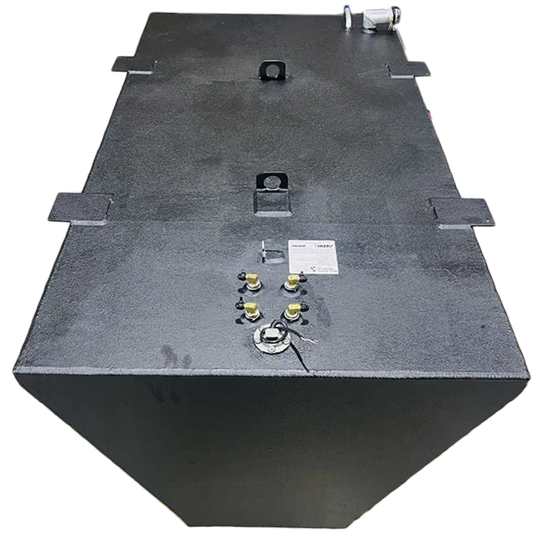 A dark grey, irregularly shaped metal tank with a textured surface is shown from an elevated perspective against a black and grey checkered background. The tank's trapezoidal side and rectangular top are visible, along with various fittings, including nozzles, caps, and what appear to be handles or mounting points, on its upper surface. A small white label is also present on the tank's top