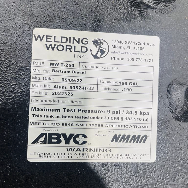 A white product label from "WELDING WORLD INC." is shown on a black, textured background. The label provides specifications for a fuel tank: Part# WW-T-250, manufactured for "Bertram Diesel," Mfg. Date 05/09/22, Capacity 166 GAL, Material Alum. 5052-H-32, Thickness .190, and Serial # 2022325. It is recommended for Diesel fuel, has a maximum test pressure of 9 psi / 34.5 kpa, meets ISO 8846 and 10088 specifications, and is certified by ABYC and NMMA.