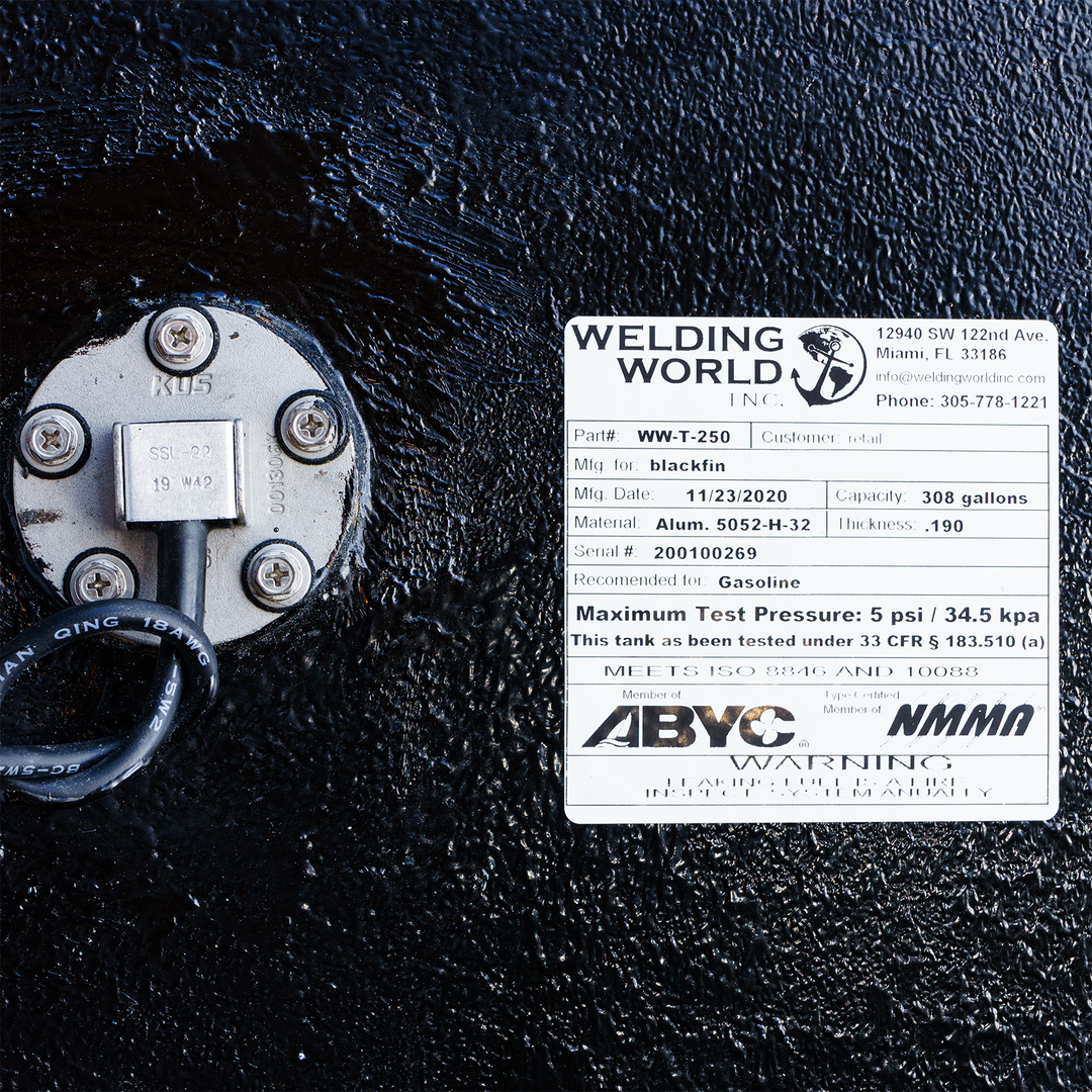 A close-up image of a specification label from Welding World Inc. for a Blackfin fuel tank, featuring details such as part number (WW-T-250), manufacturing date (11/23/2020), capacity (308 gallons), and material specifications. The label includes safety warnings regarding gasoline and maximum test pressure, alongside a circular connection point with wiring