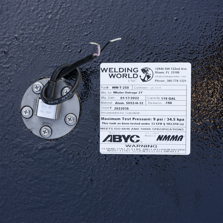 Certification label for the 117-gallon aluminum belly fuel tank installed in the 1995 Boston Whaler Outrage 21' center console. Issued by Welding World Inc. (Part #WW-T-250, Serial #2022036), the label confirms .190″ 5052-H32 marine-grade aluminum construction and gasoline compatibility. It specifies a 9 psi maximum test pressure in accordance with 33 CFR § 183.510(a), and cites compliance with ISO 8846 and ISO 10088 standards. Additional markings note ABYC and NMMA certifications. A printed warning stresse