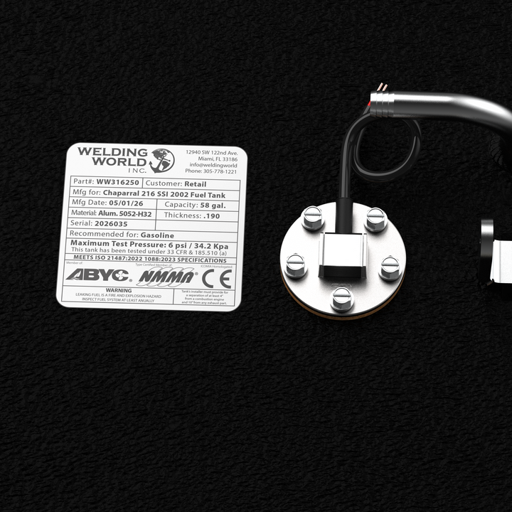 Close-up detail of the official Welding World Inc. manufacturing label and integrated fuel sending unit on a Chaparral 216 SSI (2002) fuel tank. The label confirms a 58-gallon capacity, .190" thickness 5052-H32 marine-grade aluminum construction, and compliance with ABYC, NMMA, and CE standards. Finished in protective black Coal Tar Epoxy, this tank is engineered for a guaranteed 100% drop-in fit.