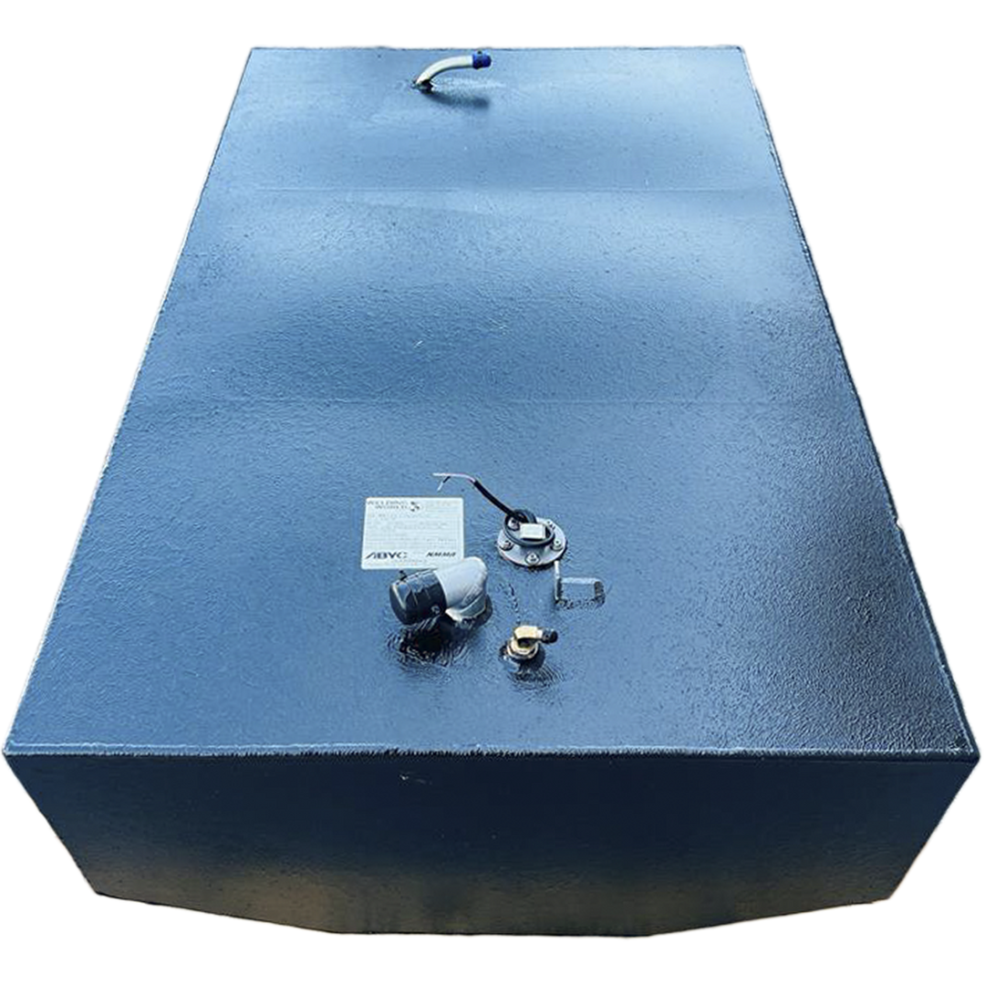 A dark, rectangular fuel tank with a textured surface is positioned against a black and grey checkered background. Various fittings, including a small curved pipe with a blue tip, a cap, a wired sensor, and other nozzles, are visible on its top surface. A white label is also present on the tank