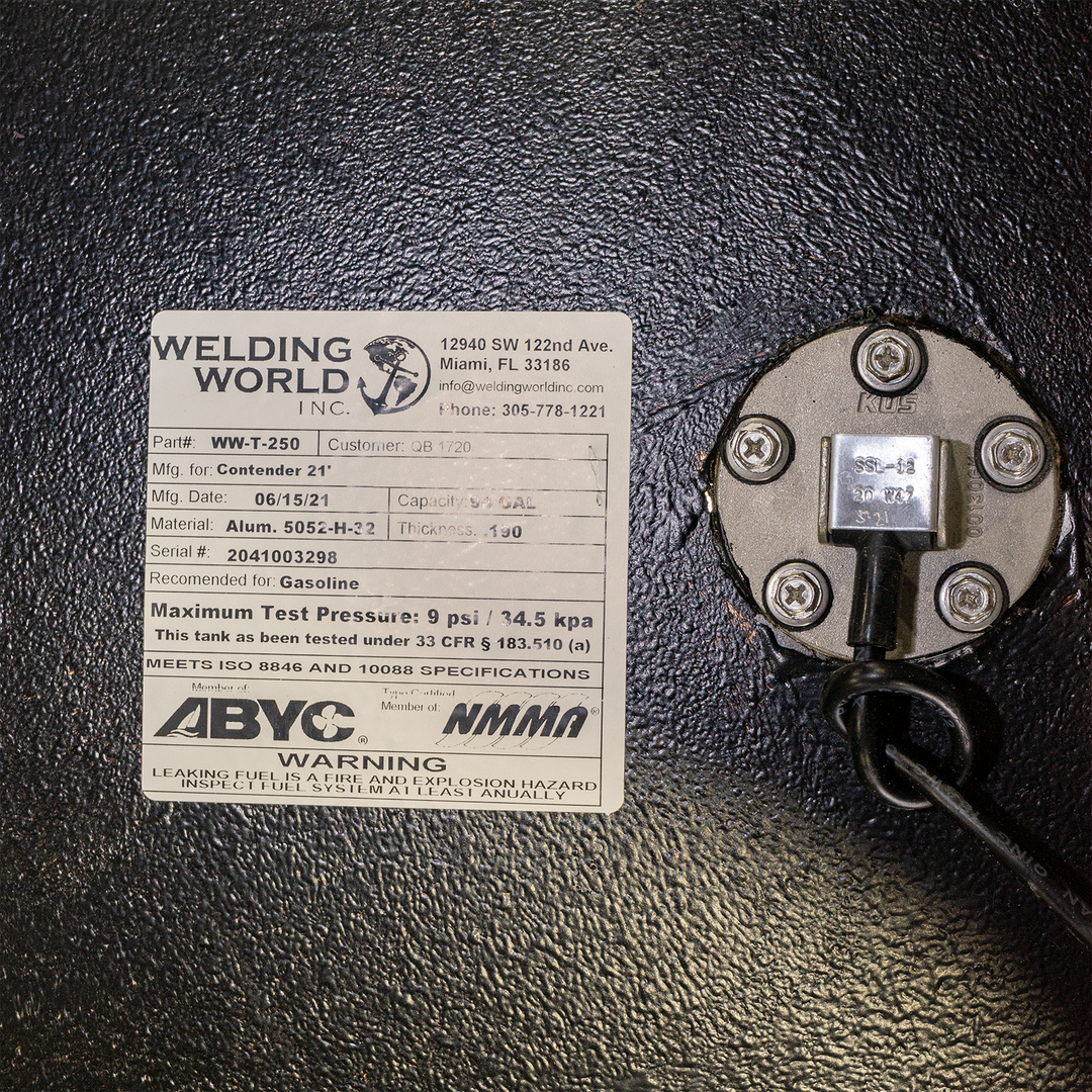 Alt text: A white product label from "Welding World Inc." is adhered to a textured black surface, likely a fuel tank. The label provides specifications for a Contender 21' fuel tank, including Part# WW-T-250, Mfg. Date 06/15/21, Material Alum. 5052-H-32, Thickness .190, and Serial# 2041003298. It also states the tank is recommended for Gasoline, has a Maximum Test Pressure of 9 psi / 34.5 kPa, and meets ISO 8846 and 10088 specifications. Certifications from ABYC and NMMA are visible