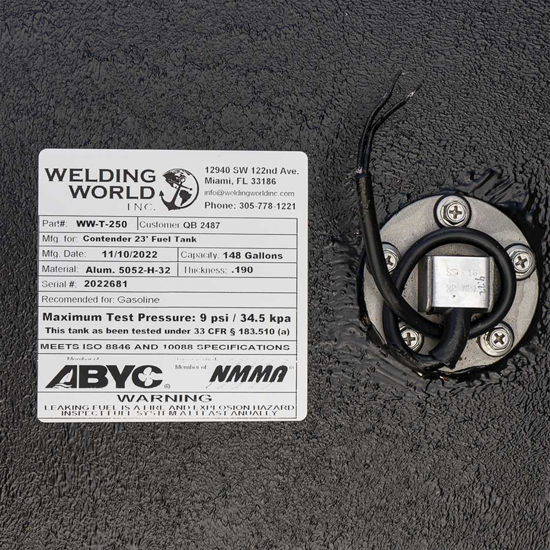 A close-up photograph shows a portion of a black textured fuel tank, focusing on a detailed manufacturer's specification label from Welding World, Inc., and an adjacent fuel sending unit. The white label specifies that the tank (part #WW-T-250, serial #2022681) was manufactured on November 10, 2022, for a Contender 23' boat. It is constructed from .190 thickness 5052-H-32 aluminum and has a capacity of 148 gallons. The label also displays ABYC and NMMA member logos and includes a safety warning