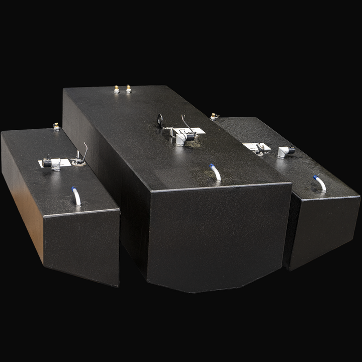 High-angle front view of three black metal fuel tanks on a transparent background. The central tank is the largest with beveled front edges, flanked by two smaller rectangular tanks on each side. Each tank has metal fittings, capped openings, wiring, and white plastic tubes on top