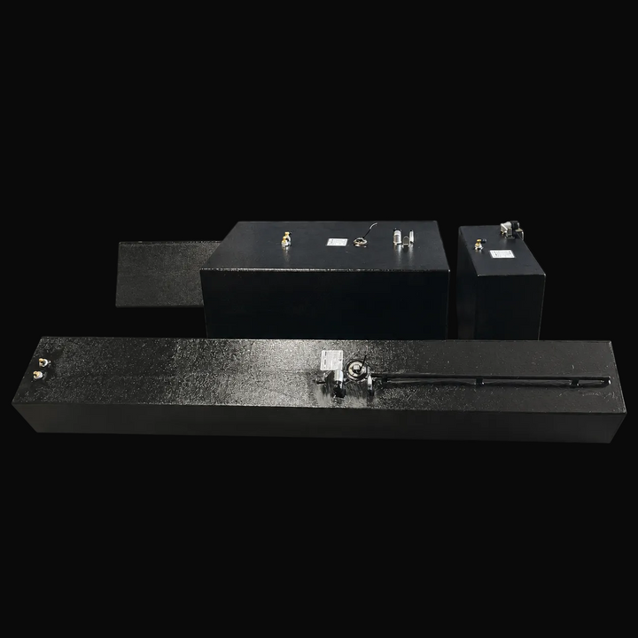 A straight, elevated side-angle perspective view of a four-tank Contender 32 multi-tank replacement marine fuel system combo from file image_a1d6c0.jpg, isolated against a black background. This alternative layout view showcases a single elongated, asymmetrical outboard saddle tank prominently positioned in the foreground, with the large central main belly fuel cell, the matching auxiliary center tank, and the second outboard saddle tank arranged clearly behind it. Precision-fabricated from heavy-gauge mari