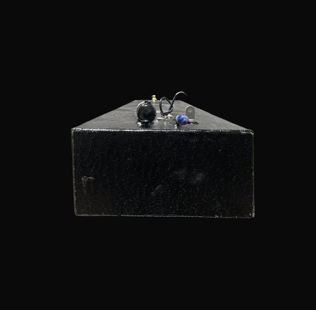 A studio front-facing end perspective view looking down the length of a physical, finished black encapsulated Eagle 17 OEM replacement marine fuel tank (29 gal 2000) from file image_495ad8.jpg, isolated against a black background. Precision-fabricated from heavy-gauge marine-grade 5052-H32 aluminum, the long low-profile rectangular body is fully encapsulated in a protective, textured black TarGard epoxy coating to resist severe saltwater pitting and bilge moisture accumulation. The top deck configuration hi