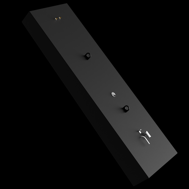 A tall, rectangular black fuel tank shown at a slight angle against a black background. The top of the tank features two lifting ears, a metal plate with a valve or plug, and several small fittings and tubes clustered near one end