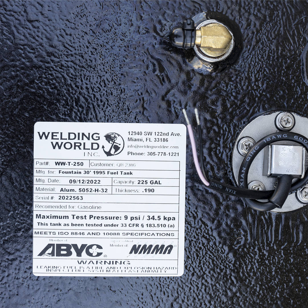 A close-up of a white manufacturer's label on a heavily textured black surface, surrounded by fittings. To the right of the label is a round, silver fuel sending unit, and a brass right-angle fitting is visible above. The "Welding World, Inc." label specifies the tank is for a "Fountain 30' 1995 Fuel Tank" with a 225-gallon capacity, made on September 12, 2022, and features ABYC and NMMA compliance logos