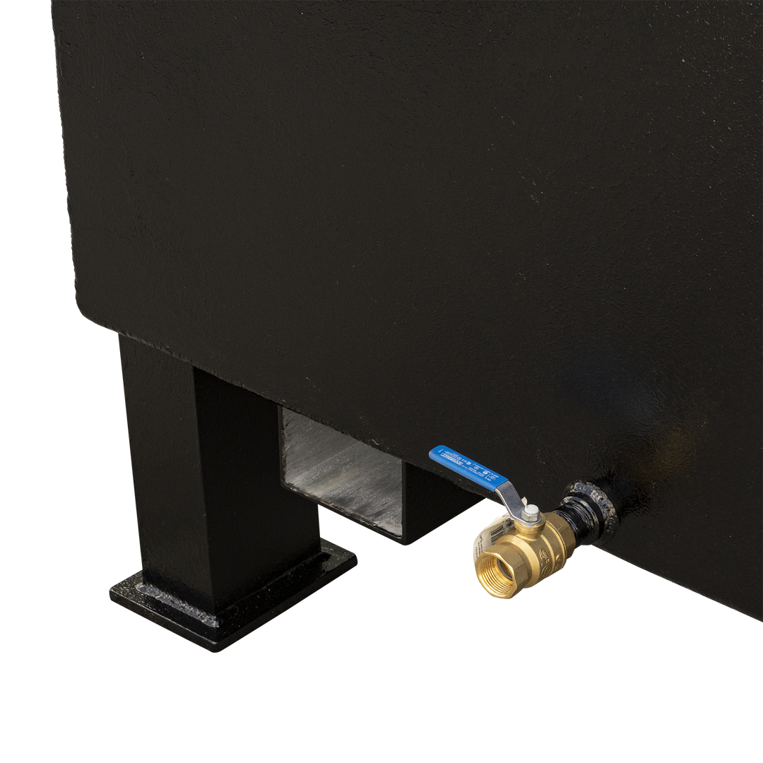 A close-up view of the bottom right side of a black, rectangular fuel tank. A brass ball valve with a blue handle is prominently attached to the tank, near a black leg and a cut-out in the tank's base