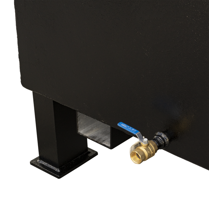 A close-up view of the bottom right side of a black, rectangular fuel tank. A brass ball valve with a blue handle is prominently attached to the tank, near a black leg and a cut-out in the tank's base