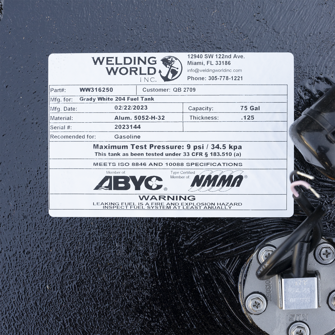 Close-up of the manufacturer's label on a Grady White 204 fuel tank by Welding World Inc., showing part number WW316250, customer QB 2709, 75-gallon capacity, manufactured on 02/22/2023. Made from 0.125-inch thick aluminum 5052-H-32, recommended for gasoline. Maximum test pressure is 9 psi. Complies with ISO 8846 and 10088, certified by ABYC and NMMA. Contact info and warning about fuel system inspection also visible