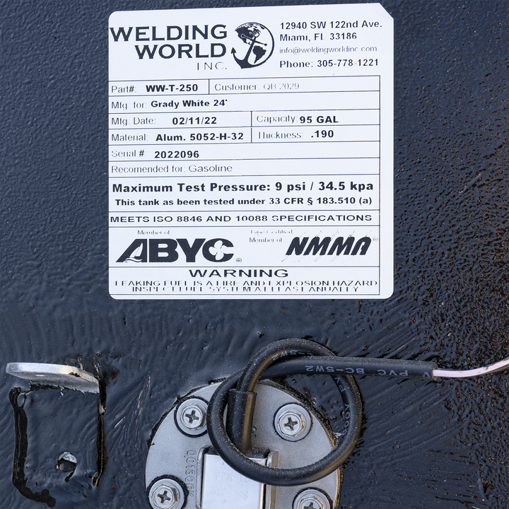 Manufactured by Welding World Inc., this 95-gallon custom aluminum fuel tank is designed for a Grady-White 24'. Label confirms construction from .190″ 5052-H32 marine-grade aluminum, gasoline compatibility, and testing to 9 psi per 33 CFR § 183.510(a). Certified to ISO 8846 and 10088, with production date of 02/11/22 and serial #2022096. Adjacent to the label is a circular sender unit with attached wiring harness—supporting electronic level sensing and system integration