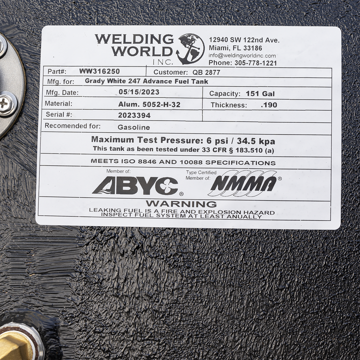 A close-up image of a Welding World Inc. label affixed to a black fuel tank. The label includes details such as part number WW316250, customer number QB 2877, and specifies that the tank is manufactured for a Grady White 247 Advance Fuel Tank. The manufacturing date is May 15, 2023, with a capacity of 151 gallons. The material is aluminum 5052-H-32 with a thickness of 0.190 inches. The serial number is 2023394, and the tank is recommended for gasoline use. It has a maximum test pressure of 6 psi (34.5 kPa)