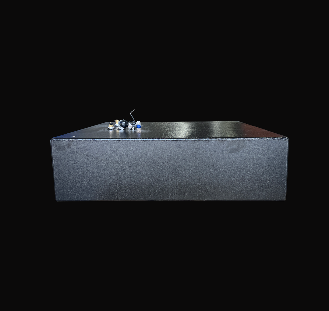 A rear profile view of the Grady White 25 Sailfish auxiliary replacement fuel tank, highlighting the thick rectangular construction and rugged black TarGard epoxy finish for superior corrosion protection. This angle emphasizes the clean, continuous lines of the heavy-duty marine-grade aluminum plate. On the top left deck, the fuel components cluster is visible, including brass fuel pickups, mechanical fittings, and electrical sending unit wiring. Built by Welding World to exact OEM specifications to guarant
