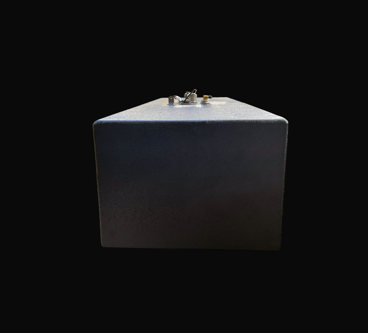 A studio head-on end perspective view looking down the length of a physical, finished black encapsulated Grady White 272 Sailfish AUX OEM replacement marine fuel tank (52 gal) from file image_2a3076.jpg, isolated against a black background. Precision-fabricated from heavy-gauge marine-grade 5052-H32 aluminum, the rectangular profile is fully encapsulated in a protective, textured black TarGard epoxy coating to resist severe saltwater pitting and bilge moisture decay. Center top deck hardware features a pre-