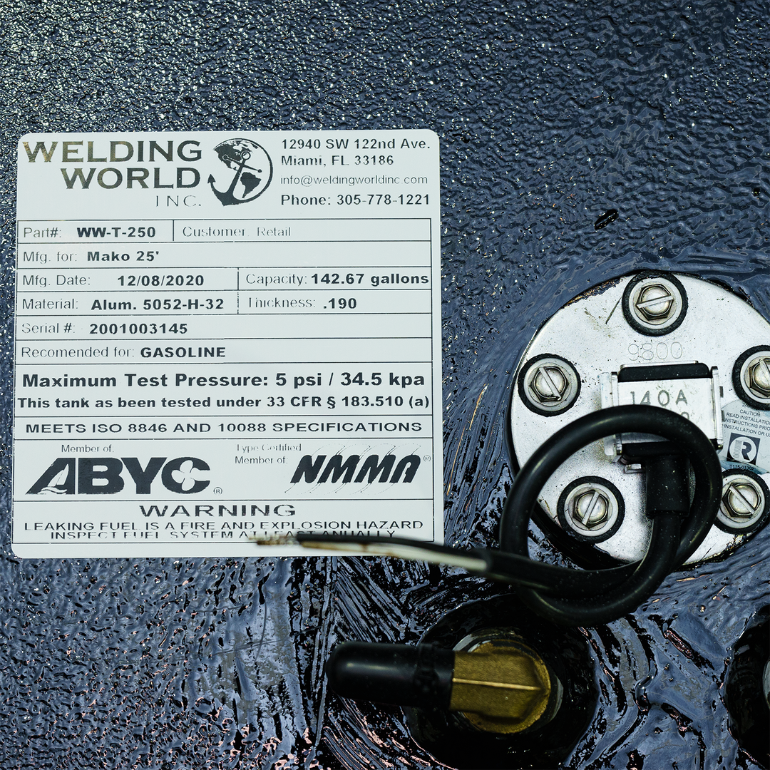 A rectangular product label from "Welding World Inc." is affixed to a black, textured surface. The label details a fuel tank with part number WW-T-250, manufactured for Mako 25' on 12/08/2020, with a capacity of 142.67 gallons. It is made of Aluminum 5052-H-32 with a thickness of .190 and has a serial number 2001003145. It's recommended for gasoline and has a maximum test pressure of 5 psi / 34.5 kpa. The tank meets ISO 8846 and 10088 specifications and the manufacturer is a member of ABYC and NMMA
