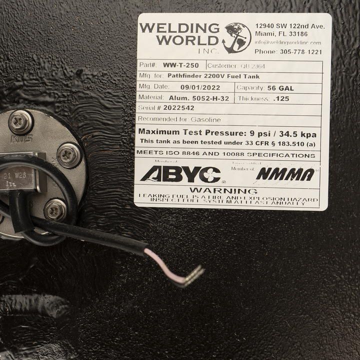 A close-up view of a product label from 'Welding World Inc.' affixed to a textured black surface. The label details specifications for a 'Pathfinder 2200V Fuel Tank,' including part number WW-T-250, manufacturing date 09/01/2022, material Alum. 5052-H-32, capacity 56 GAL, and a maximum test pressure of 9 psi. It also states compliance with ISO 8846 and 10088 specifications, and features ABYC and NMMA logos. A warning about leaking fuel being a fire and explosion hazard is visible at the bottom.
