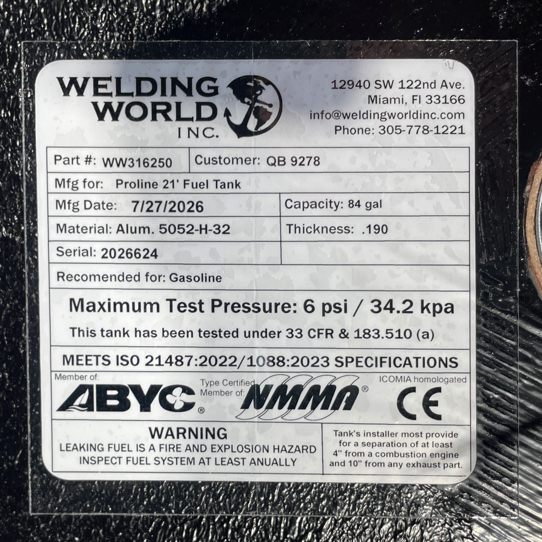 A macro top-down view of the official manufacturer certification tag on a physical, finished black encapsulated Proline 21 OEM replacement marine fuel tank (84 gal 1994) from file image_15213e.jpg. Adhered to the textured black TarGard epoxy coating, the weather-resistant specification label from Welding World Inc. (Miami, FL) lists part number WW316250, heavy-gauge Alum. 5052-H-32 material, extra-thick .190 thickness, an 84 gal capacity, gasoline recommendation, 6 psi / 34.2 kpa maximum test pressure under