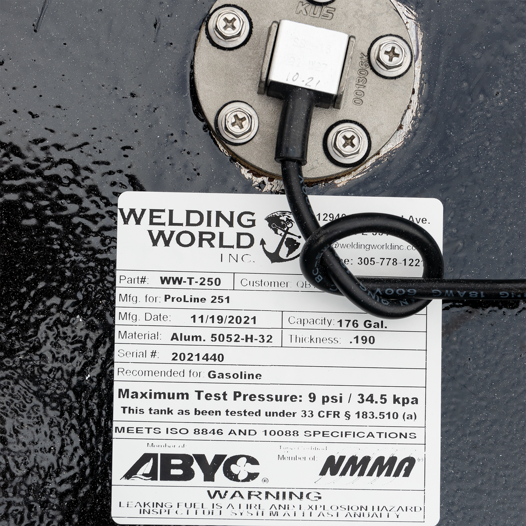 A close-up shot of a black, textured surface, likely a fuel tank, featuring a metal gauge secured by four screws and a white label from "WELDING WORLD INC." The label provides detailed specifications for a ProLine 251 fuel tank, including part number WW-T-250, manufacturing date 11/19/2021, capacity 176 gallons, material Alum. 5052-H-32, thickness .190, serial number 2021440, recommended for Gasoline, and a maximum test pressure of 9 psi / 34.5 kpa. It also states that the tank meets ISO 8846