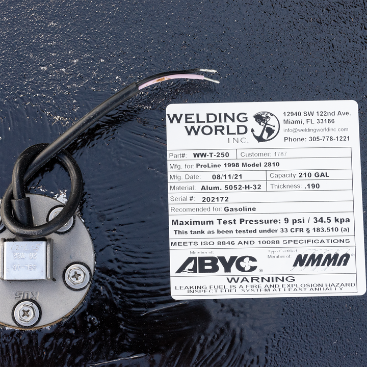 A white label on a black fuel tank, detailing specifications for a 210-gallon fuel tank for a ProLine 1998 Model 2810, manufactured by Welding World Inc. on 08/11/21. The label includes the part number WW-T-250, material as Alum. 5052-H-32 with a thickness of .190, serial number 202172, and states it is recommended for gasoline with a maximum test pressure of 9 psi / 34.5 kpa. It also notes that the tank meets ISO 8846 and 10088 specifications and is a member of ABYC and NMMA, with a warning about leaking