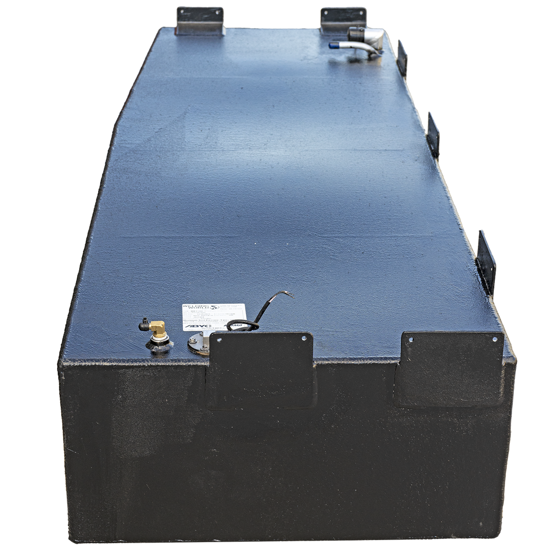 A black, rectangular fuel tank with a textured surface is positioned against a checkerboard background, viewed from an angled perspective. The top surface of the tank features various metal fittings and connections, including a small brass valve, a white label, and a black wire extending from a circular fixture. Along the sides of the tank, several rectangular black brackets are visible, some with small circular holes