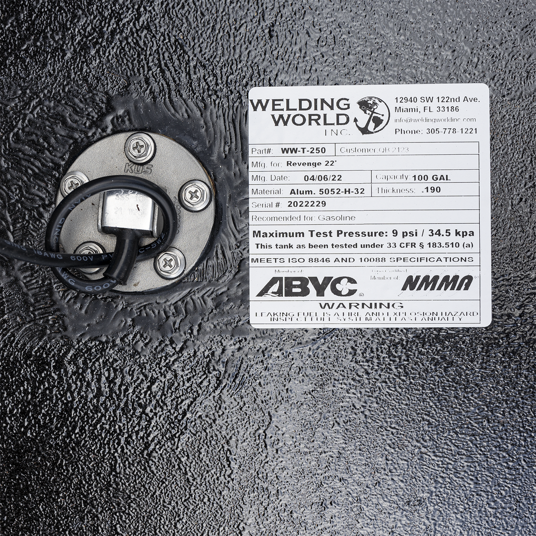 A white product label from "Welding World Inc." affixed to a textured black surface. The label provides details for a "Revenge 22'" fuel tank, including Part# WW-T-250, a manufacturing date of 04/06/22, material of Alum. 5052-H-32, a capacity of 100 gallons, and a thickness of .190. It also specifies a maximum test pressure of 9 psi / 34.5 kpa, and indicates compliance with ISO 8846 and 10088 specifications, as well as ABYC and NMMA memberships. A circular metallic component with wires and screws is visible