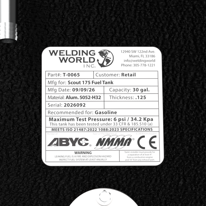 A close-up studio top-down view showcasing the official Welding World Inc. manufacturing certification and compliance specification label on a black TarGard epoxy-coated Scout 175 replacement marine fuel tank (30 gal) from file image_c33d8b.jpg against a dark background. The detailed data plate clearly displays Part # T-0065, customer type, manufacturing date, Alum. 5052-H32 material with .125 thickness, 6 psi test pressure, ABYC, NMMA, and CE compliance standards, alongside the electronic fuel level sendin