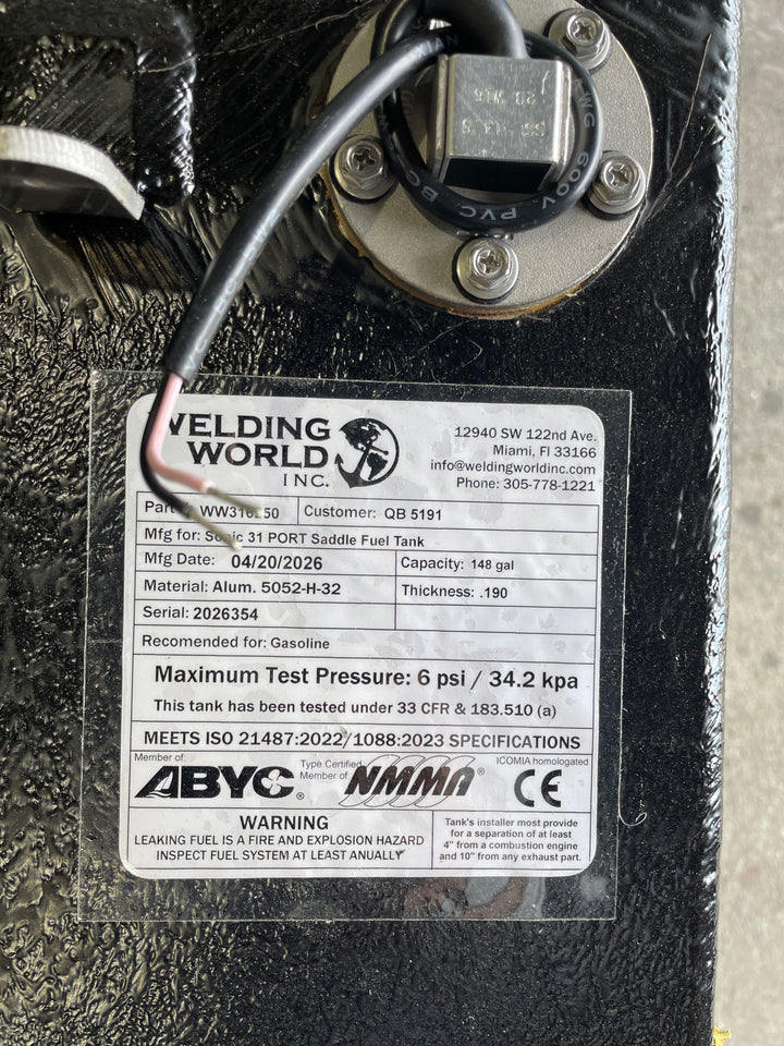 Close-up of the Welding World Inc. manufacturing label for a Sonic 31 Port Saddle fuel tank replacement. The certification tag confirms a 148-gallon capacity, heavy-duty .190" thickness 5052-H32 aluminum construction, and 6 psi maximum test pressure. The label shows full compliance with USCG 33 CFR § 183.510(a), ABYC, NMMA, and CE standards, ensuring a safe and legal OEM-quality replacement for marine gasoline systems.
