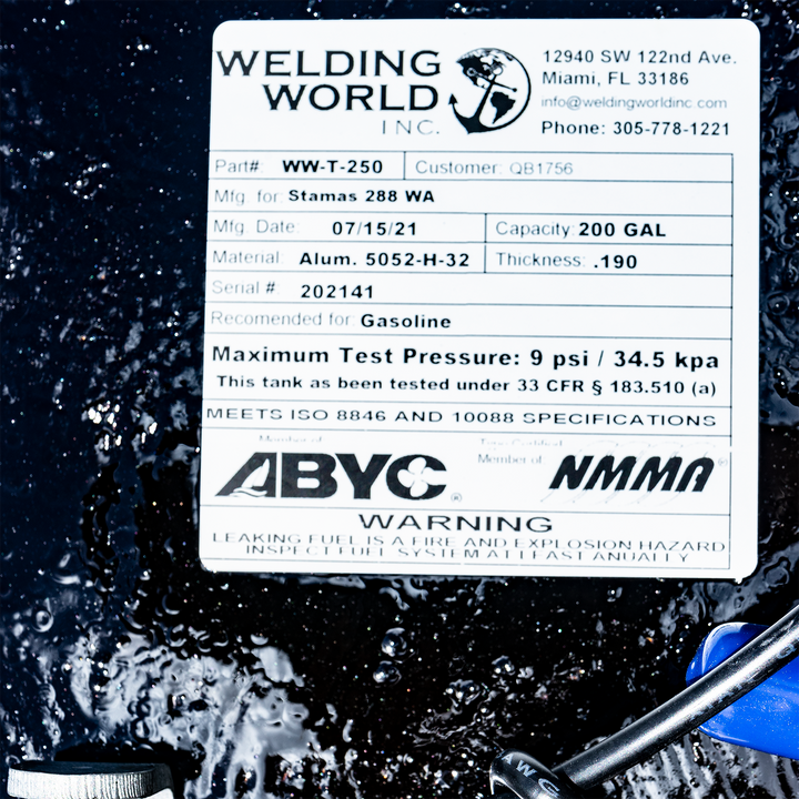 A close-up of a product label for a Welding World Inc. WW-T-250 fuel tank, customer QB1756. It was manufactured on July 15, 2021, for a Stamas 288 WA, with a capacity of 200 gallons. The tank is made from 0.190-inch thick Aluminum 5052-H-32, has serial number 202141, and is recommended for gasoline. It lists a maximum test pressure of 9 psi / 34.5 kpa and states it meets 33 CFR § 183.510 (a), ISO 8846 and 10088 specifications. The label also shows memberships with ABYC and NMMA,